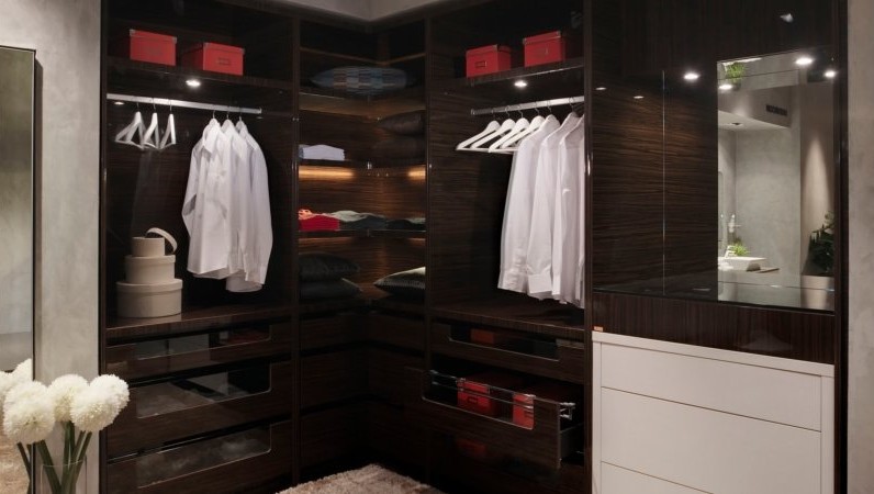 Walk-in wardrobe with dark timber and lit shelving